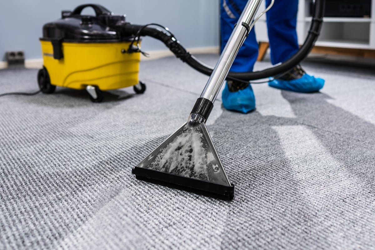 Janitor cleaning carpet with a vacuum cleaner